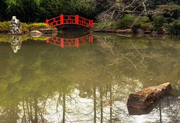 $A Red Bridge Over Still Water.webp