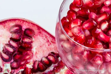 $Pomegranate and Glass of seeds on black - close up.webp
