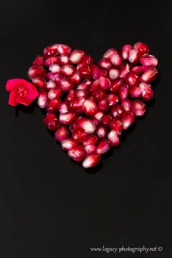 $pomegranate seed heart with flower on black.webp