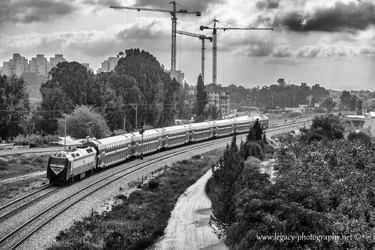 $Train on tracks - buildings trees and cranes in background - High contrast  BW.webp
