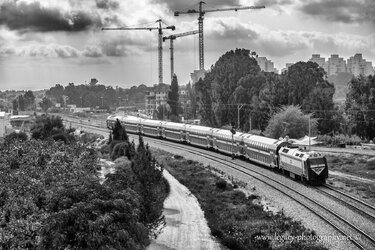 $Train on tracks - buildings trees and cranes in background - High contrast  BW right to left.jpg