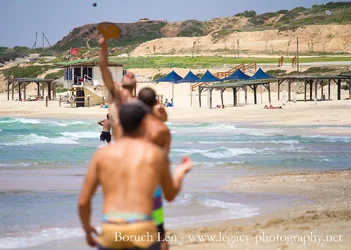 $Shirtless guys playing ball on the beach waves.webp