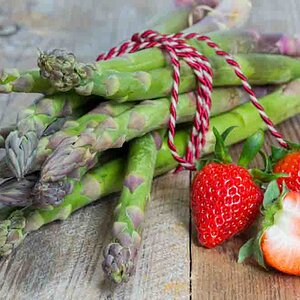 Green asparagus with strawberries on wooden