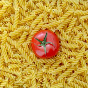 Tomato with fusilli pasta as background