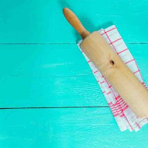 Rolling pin and tea towel on turquoise wooden background