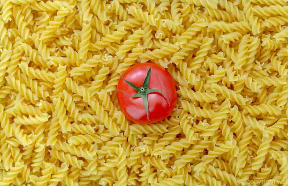 Tomato with fusilli pasta as background